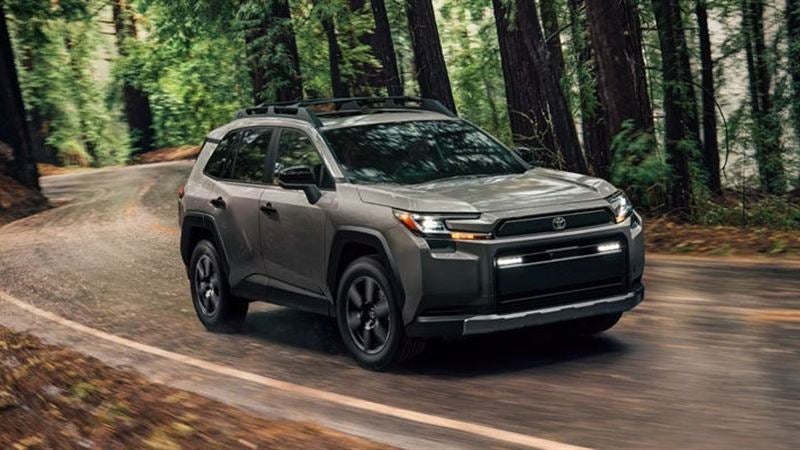 Toyota-supplied image of a 2026 RAV4 driving along a winding road through a forest.
